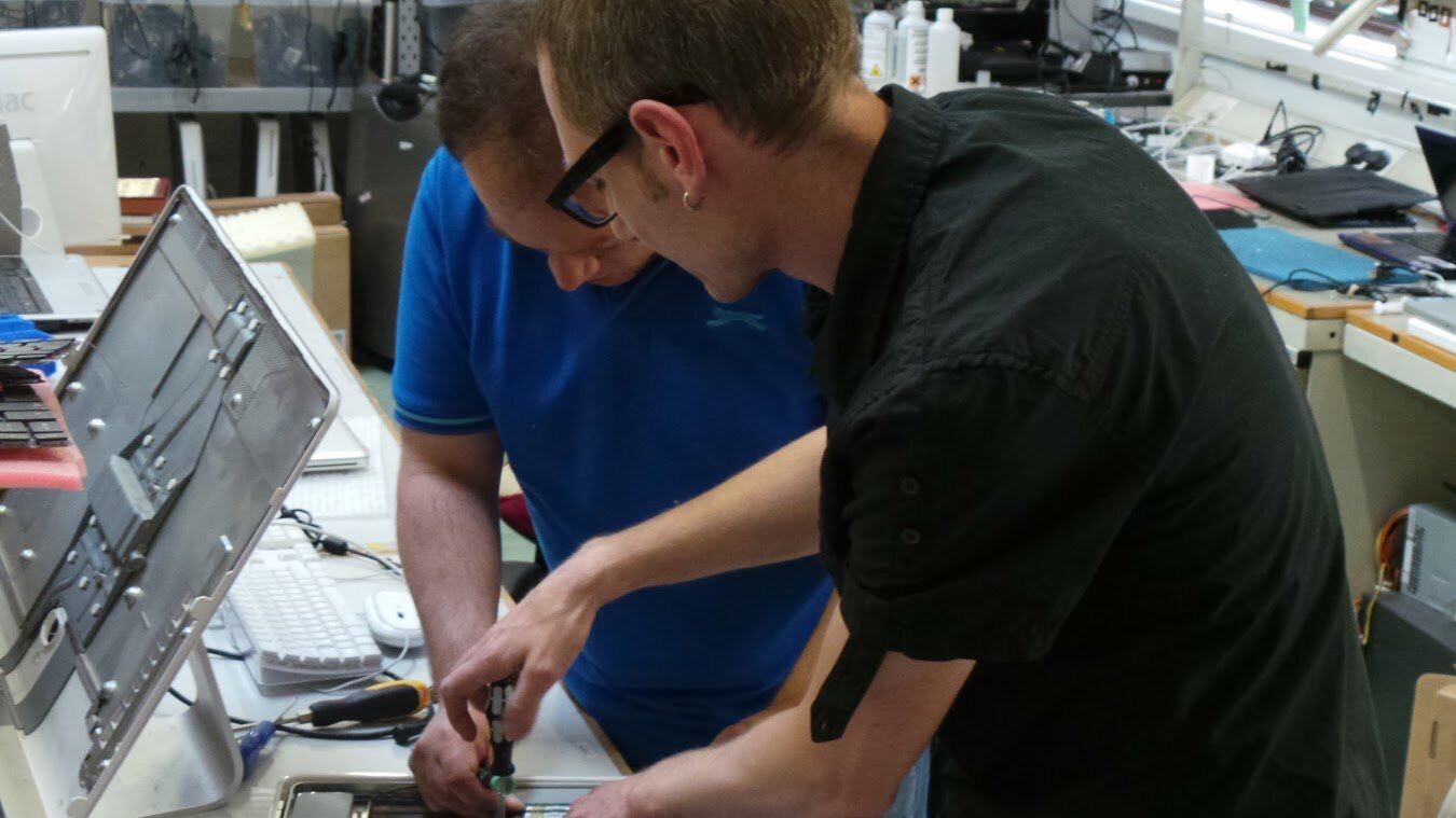 Two technicians repairing a computer at the workshop bench